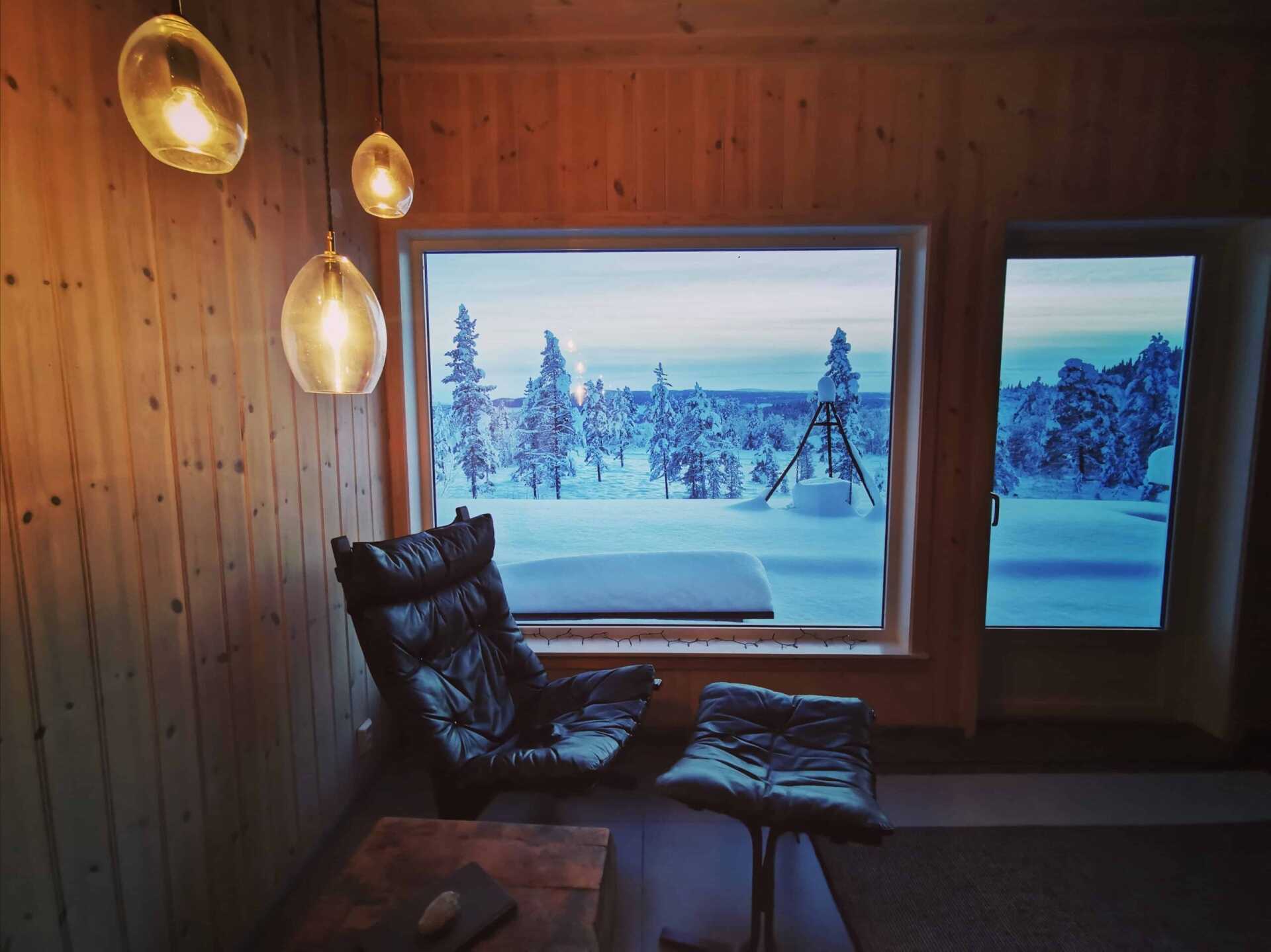 A cabin armchair beside a window full of winter forest